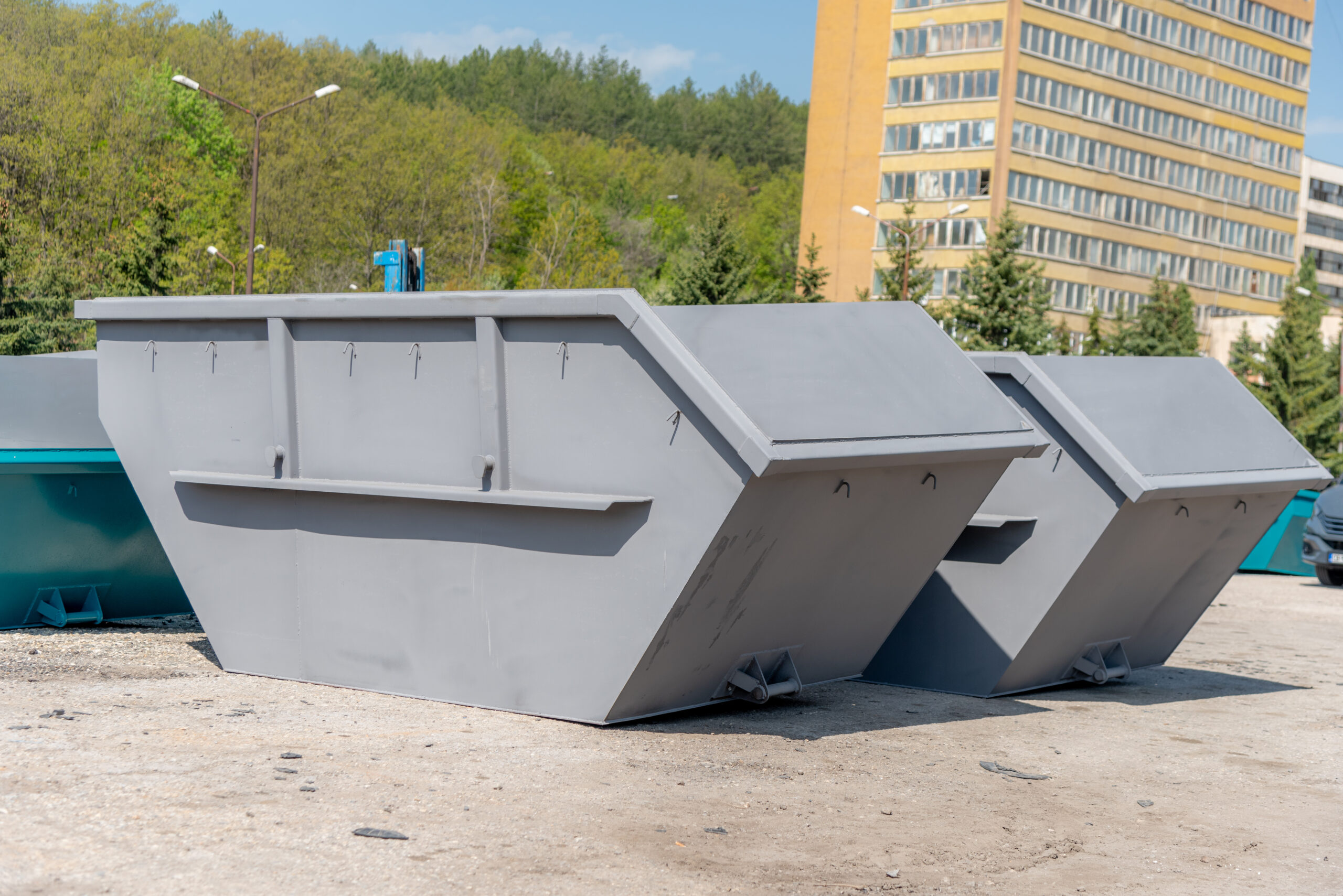 Grey construction-waste skip containers in a yard