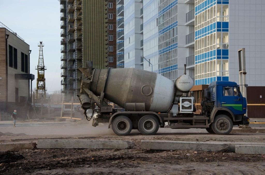 Concrete mixer truck on a construction site beside a high-rise