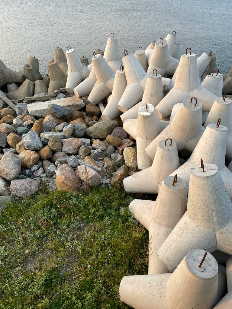 New concrete tetrapods on a breakwater beside a rock core and the sea